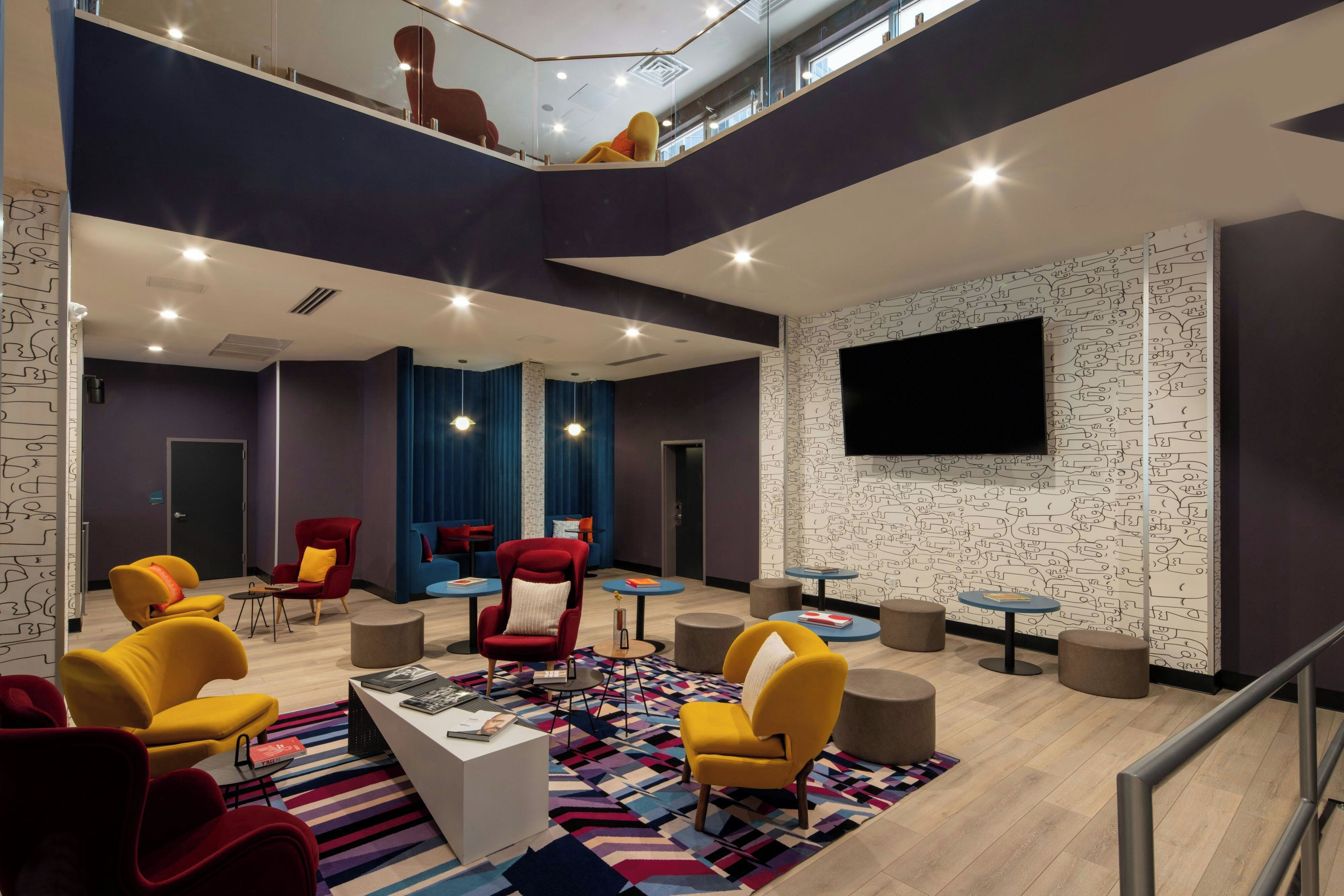 A modern lounge area with seating, a flat-screen TV, and a patterned wall.
