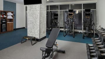 Un gimnasio con cintas de correr, elípticas y un banco.