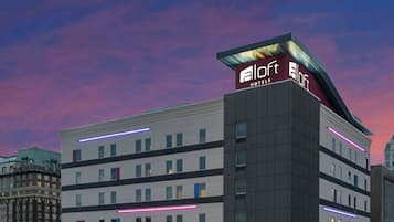 A multi-story hotel with a modern design, featuring a prominent logo at the top.