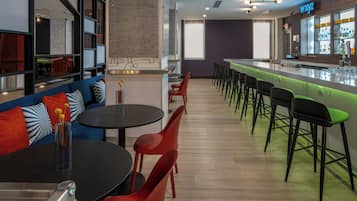 A modern bar area with a bar counter, stools, and a seating area with tables and chairs.