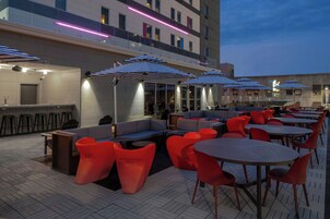 Un espacio al aire libre con mesas y sillas, una zona de bar y una piscina.