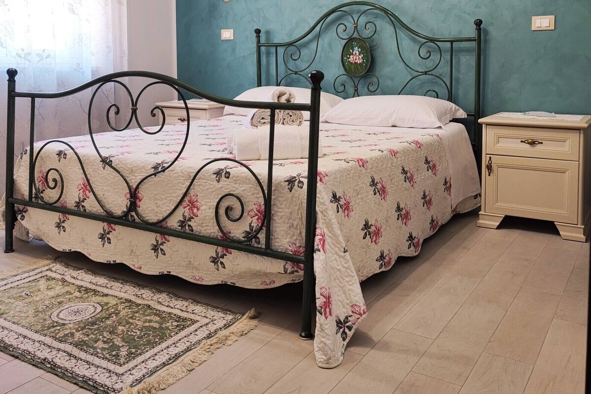 Une chambre à coucher avec un lit, une table de chevet, une lampe fixée au mur et un tableau.