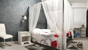 A bedroom with a four-poster bed, a bedside table, a chair, and a small shelf. - Guest House Elettra di Siracusa (Syracuse)
