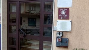 A building entrance with a large glass door, a mailbox, and a potted plant. - Guest House Elettra di Siracusa (Syracuse)