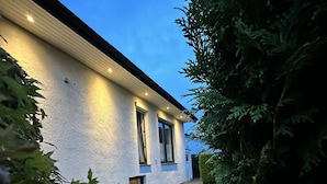Ein modernes Haus mit weißer Fassade, großen Fenstern und einem gepflegten Rasen.