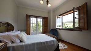 Ein Schlafzimmer mit einem Bett, einem Sessel, einem Fenster mit Blick und einer Tür.