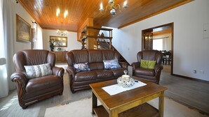 Ein geräumiges Wohnzimmer mit Ledersofas, einem Holztisch und einer Chandelier.