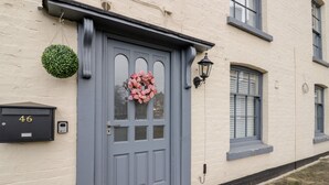 A grey door with a pink floral wreath, a mailbox with the number 46, and a small green plant hanging above it. - The Fox (Bridgnorth)