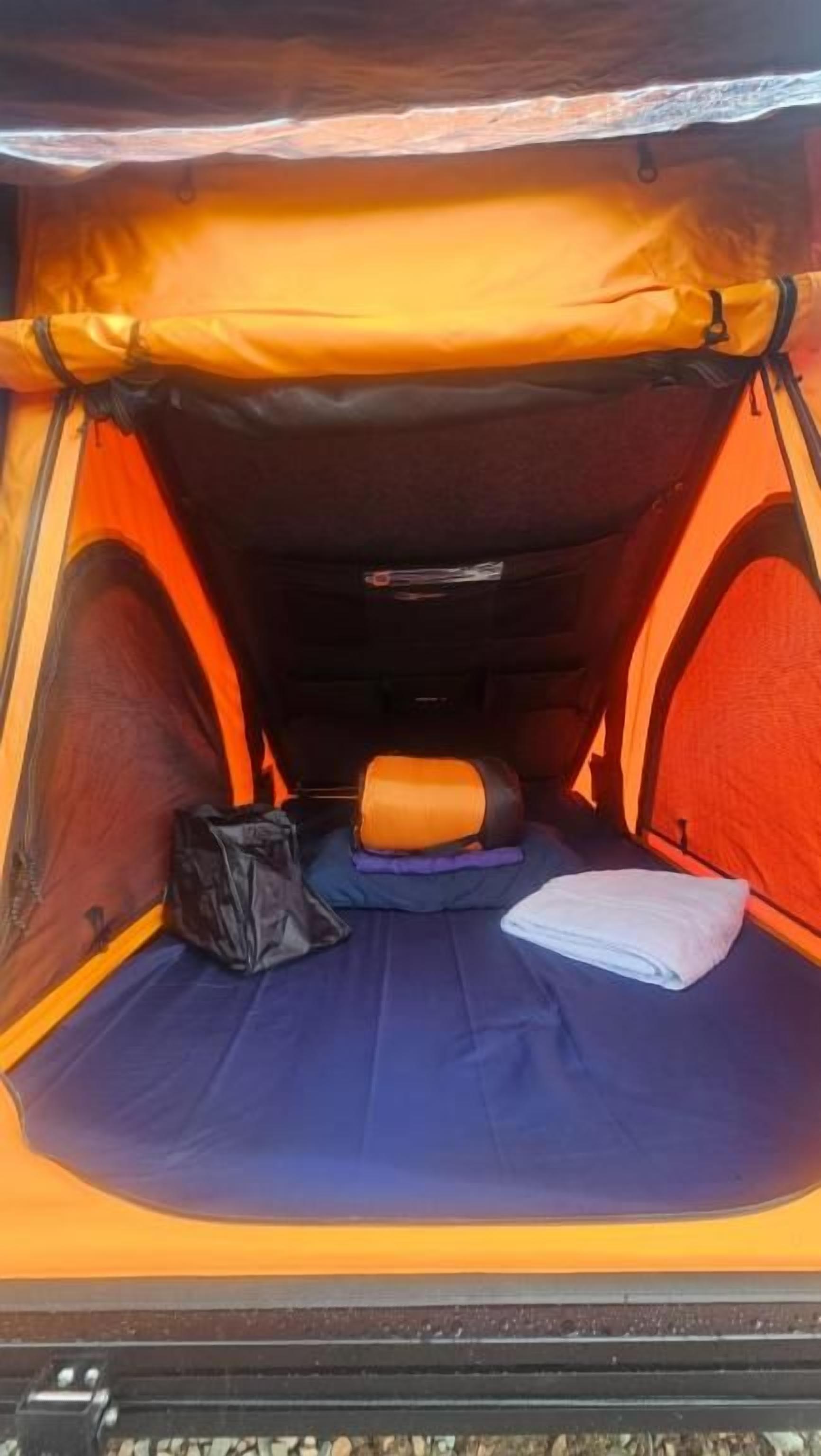A tent interior with a sleeping area, a bag, and a folded towel.