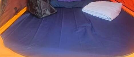 A tent interior with a sleeping area, a bag, and a folded towel.