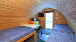 A small, wooden cabin with two sleeping areas, a kitchenette, and a television. - Glamping Pods (Kinlochleven)