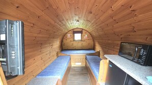 A compact RV interior with two sleeping areas, a kitchenette, and a small window. - Glamping Pods (Kinlochleven)