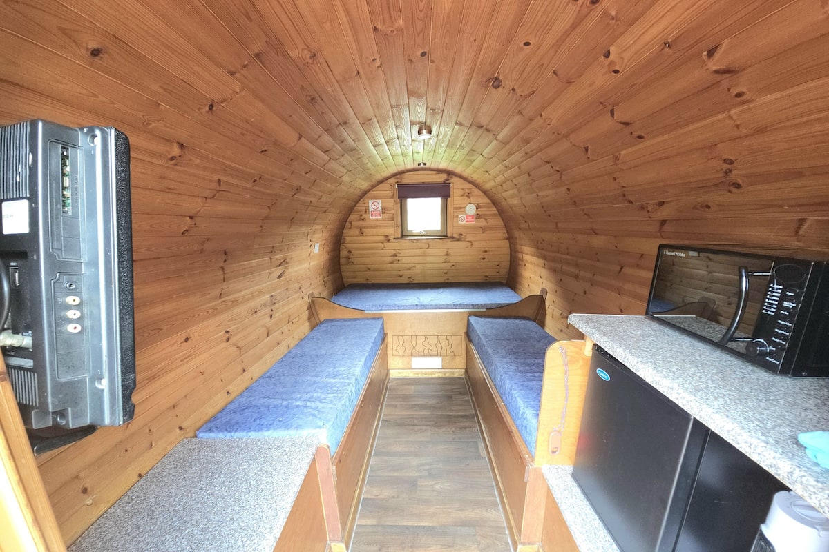 Un intérieur de camping-car compact comprenant deux espaces nuit, un coin cuisine et une petite fenêtre.