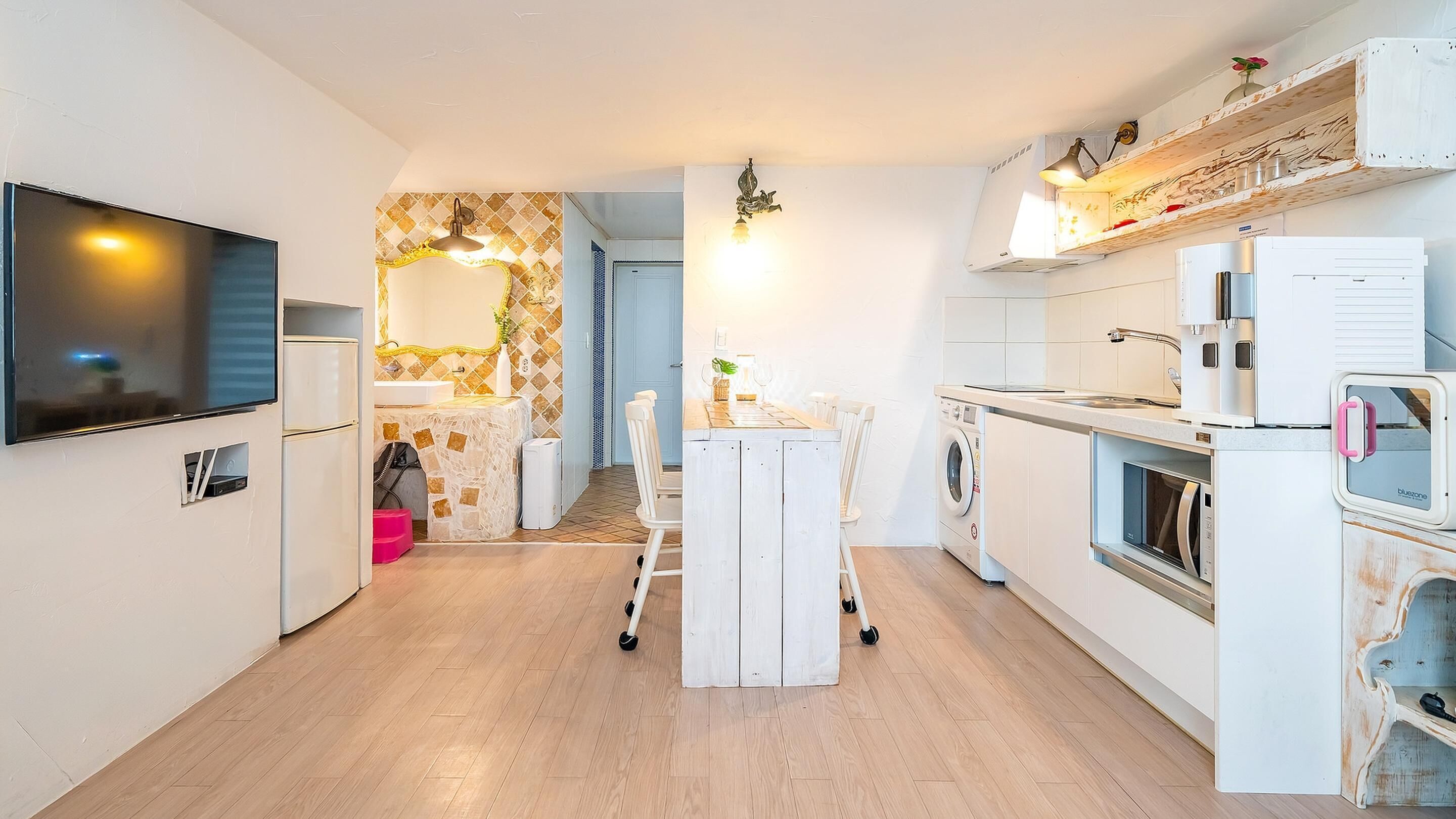 A compact kitchen with a TV, a washing machine, and a microwave.