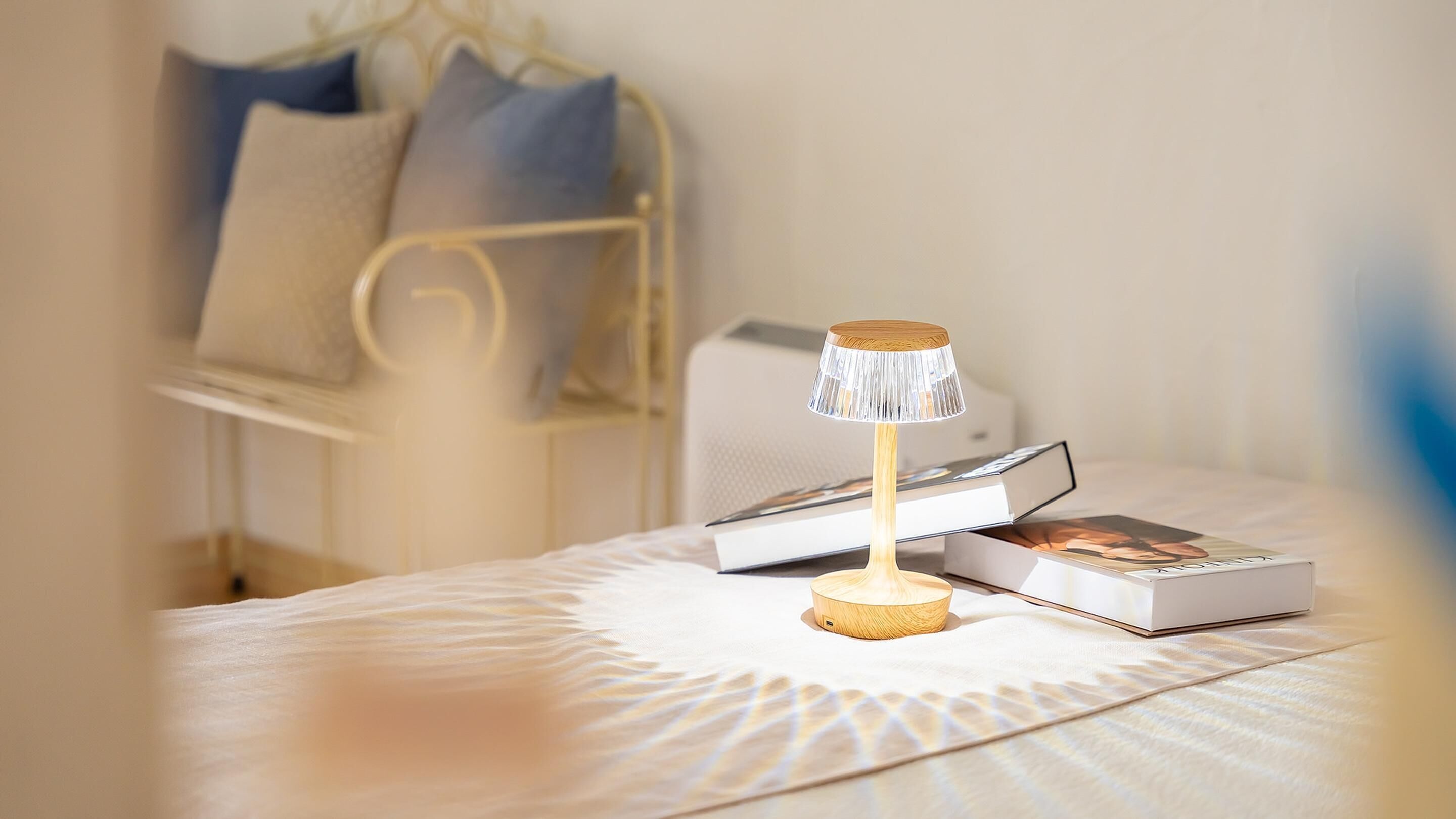 A neatly made bed with a patterned bedspread, a bedside table with a lamp, and a few books.