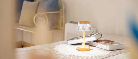 A neatly made bed with a patterned bedspread, a bedside table with a lamp, and a few books.