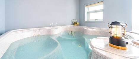 Un bain à remous doté d’un système de chauffage intégré, d’une fenêtre et d’une lanterne décorative.