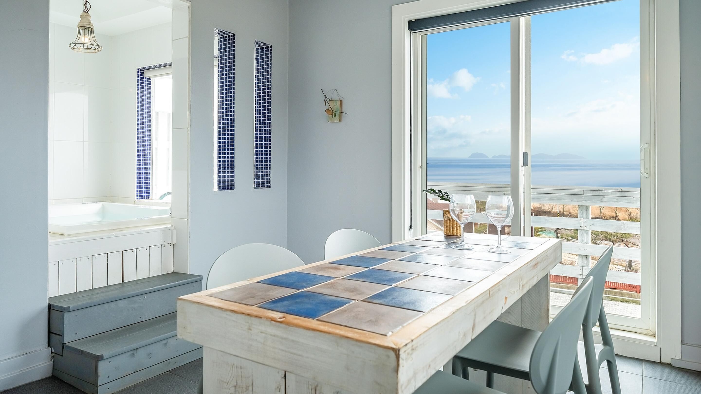 A modern kitchen with a large window, a tiled backsplash, and a wooden table with chairs.