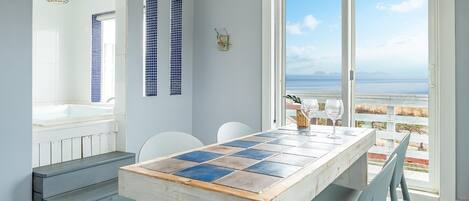 A modern kitchen with a large window, a tiled backsplash, and a wooden table with chairs.