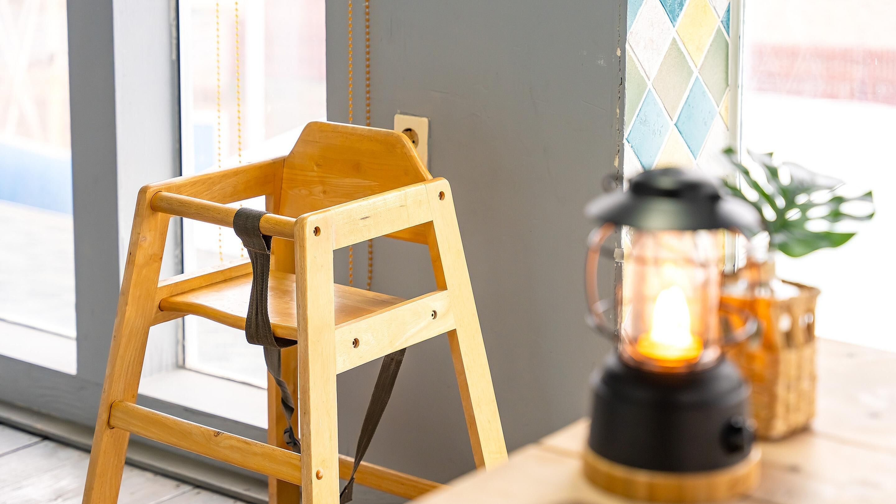 Una silla de madera con respaldo y asiento, ubicada al lado de una mesa con un farol encendido.
