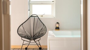 A room with a black wire chair, a white bathtub, and a lantern on the edge. - Ganghwa Imspa Pension (Incheon)