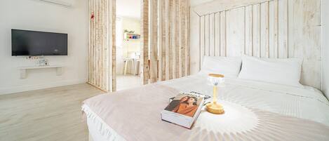 Ein Schlafzimmer mit einem Bett, einem Nachttisch mit Lampe, einem Wandfernseher und einem Bücherregal.