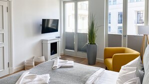 A modern hotel room with a bed, a TV, a potted plant, and a yellow chair. - Pool und Sauna mit Meerblick, Direkt an der Seebrücke - First Sellin Fewo 3.8 (Ostseebad Sellin)