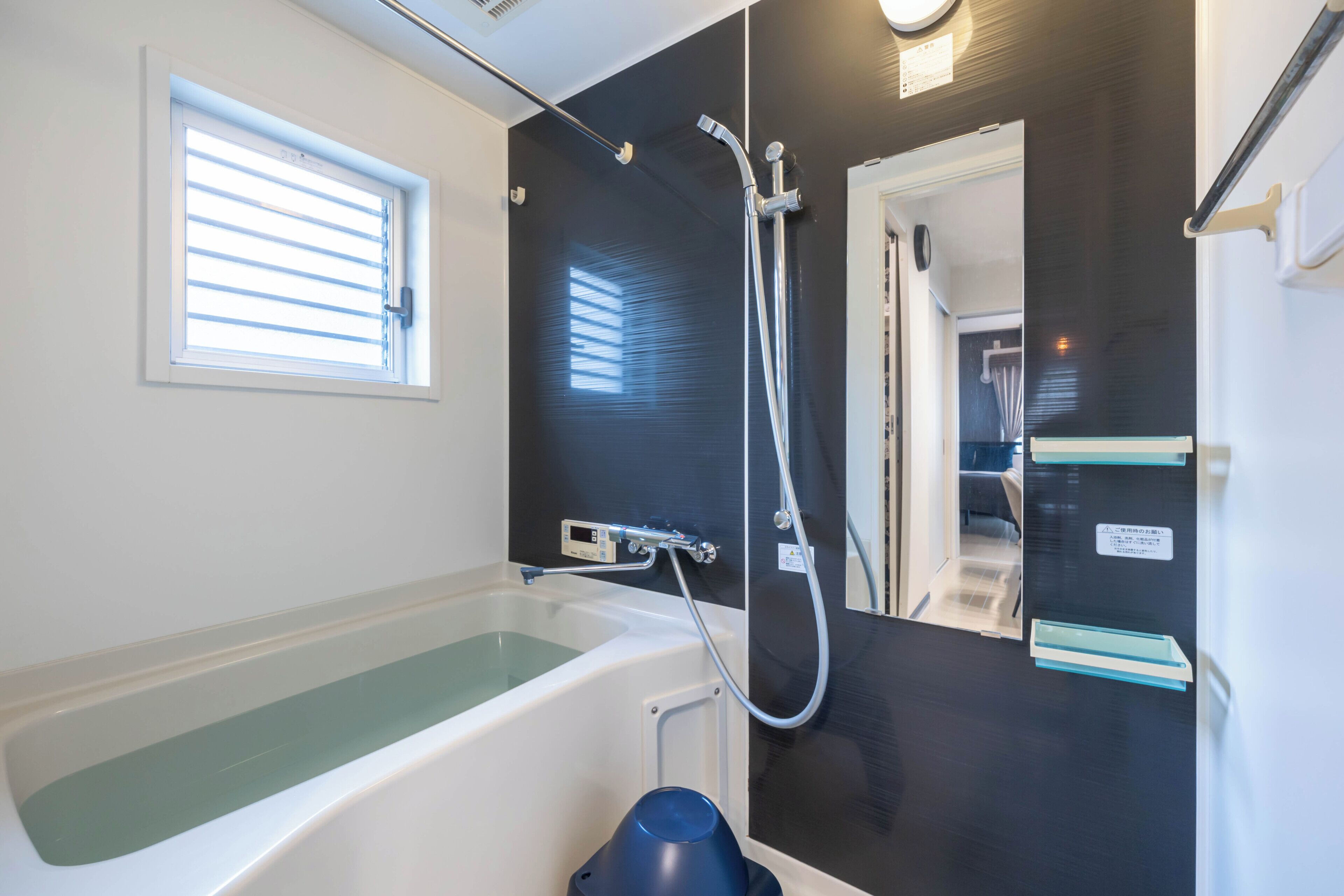 A modern bathroom with a bathtub, a shower, and a window.