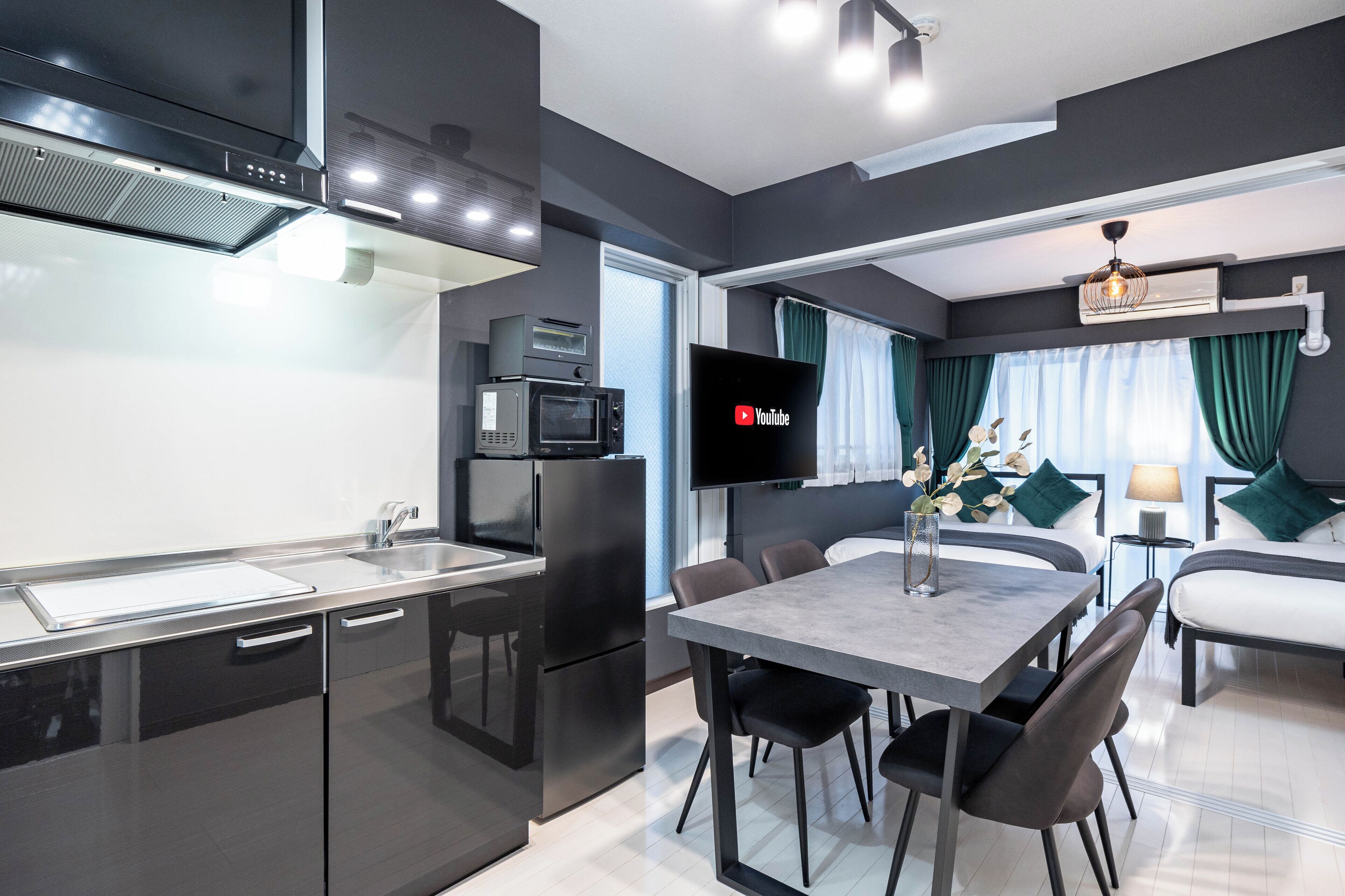 Una cucina moderna con una TV a schermo piatto, un'area pranzo con tavolo e sedie, e un soggiorno con divano e lampada.