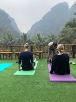 Tres personas sobre esterillas de yoga al aire libre, con montañas de fondo.