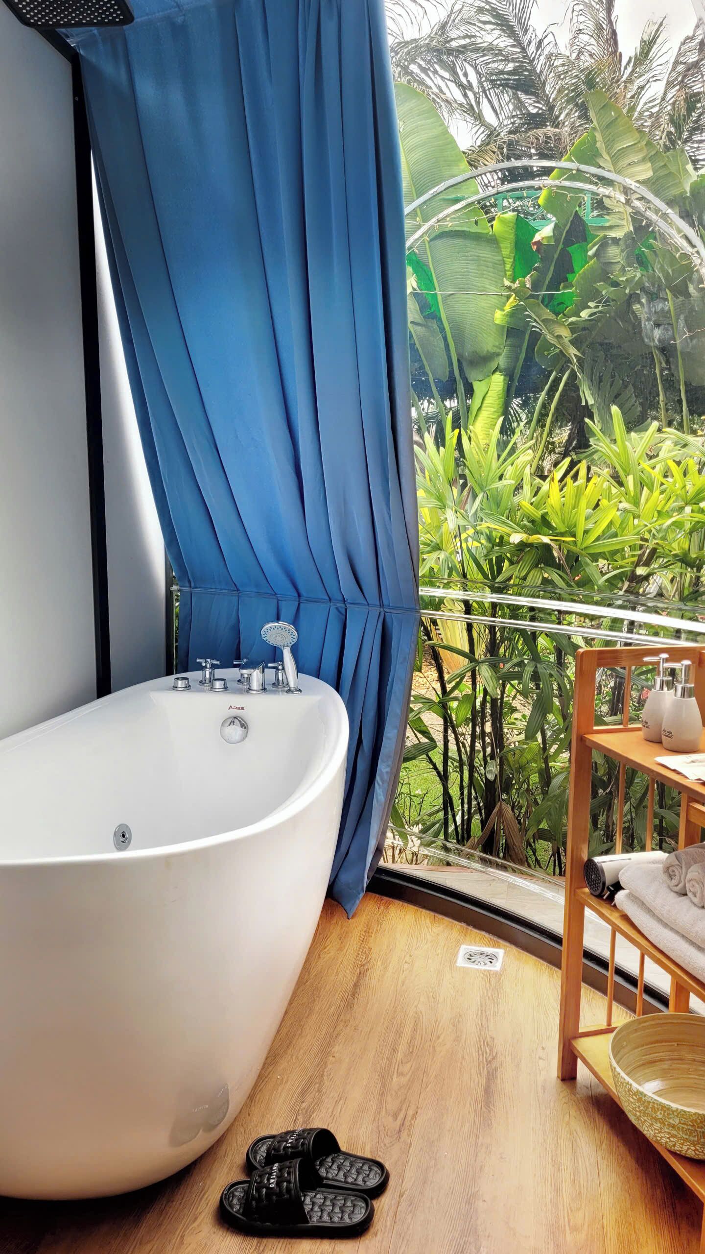 A bathroom with a freestanding bathtub, a showerhead, and a wooden shelf with toiletries.