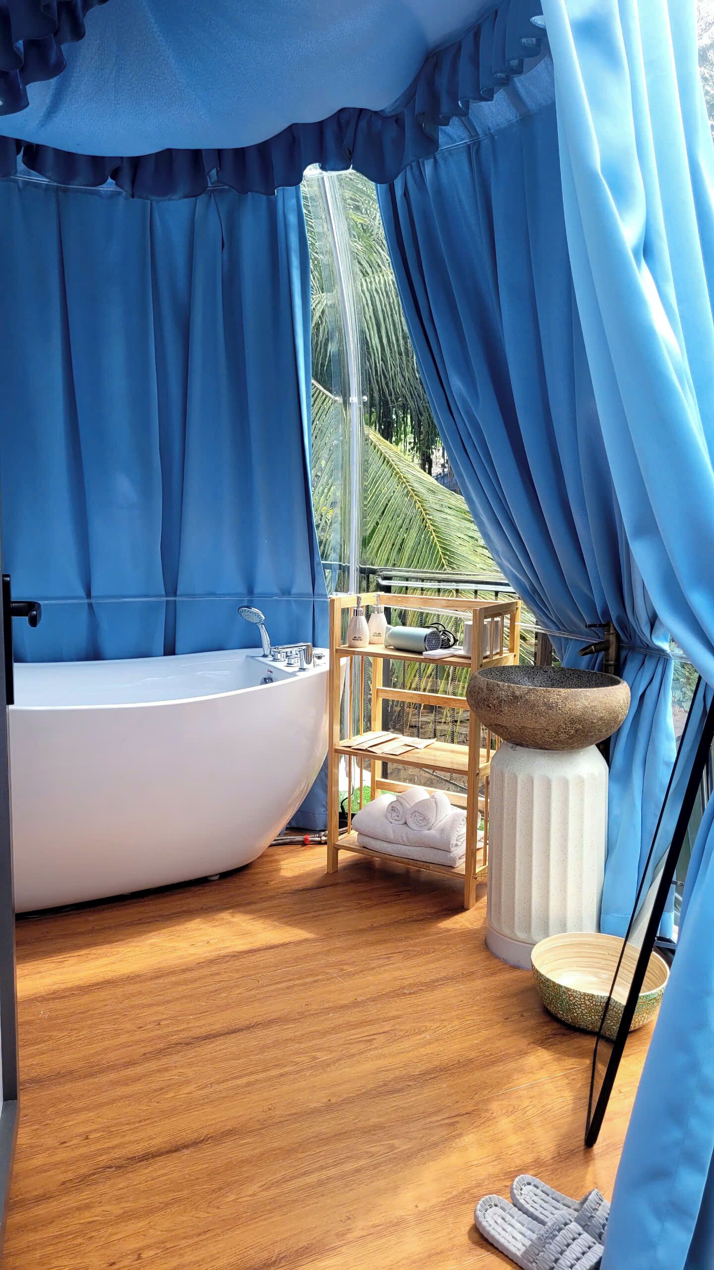 Une salle de bain avec une baignoire, une étagère en bois avec des serviettes et un lavabo en pierre.