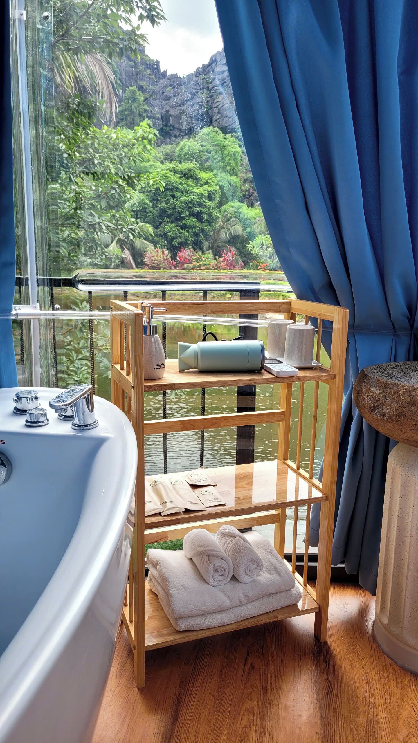 A bathroom with a bathtub, a wooden shelf with towels, and toiletries.