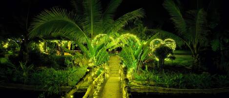 A pathway lined with illuminated heart-shaped decorations and palm trees at night.