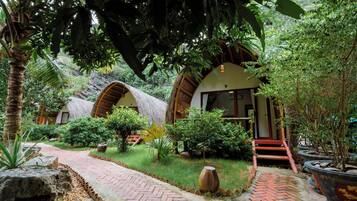 Un complexe hôtelier tropical doté de bungalows aux toits de chaume, d’un sentier dallé et d’une végétation luxuriante.