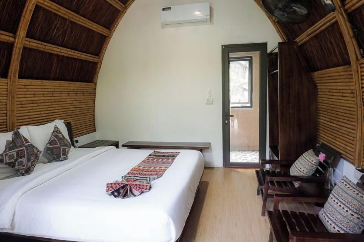 A room with a bed, a bench, and a door leading outside.