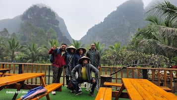 Un gruppo di persone che posa su un molo di legno con vista su un paesaggio montuoso e palme.