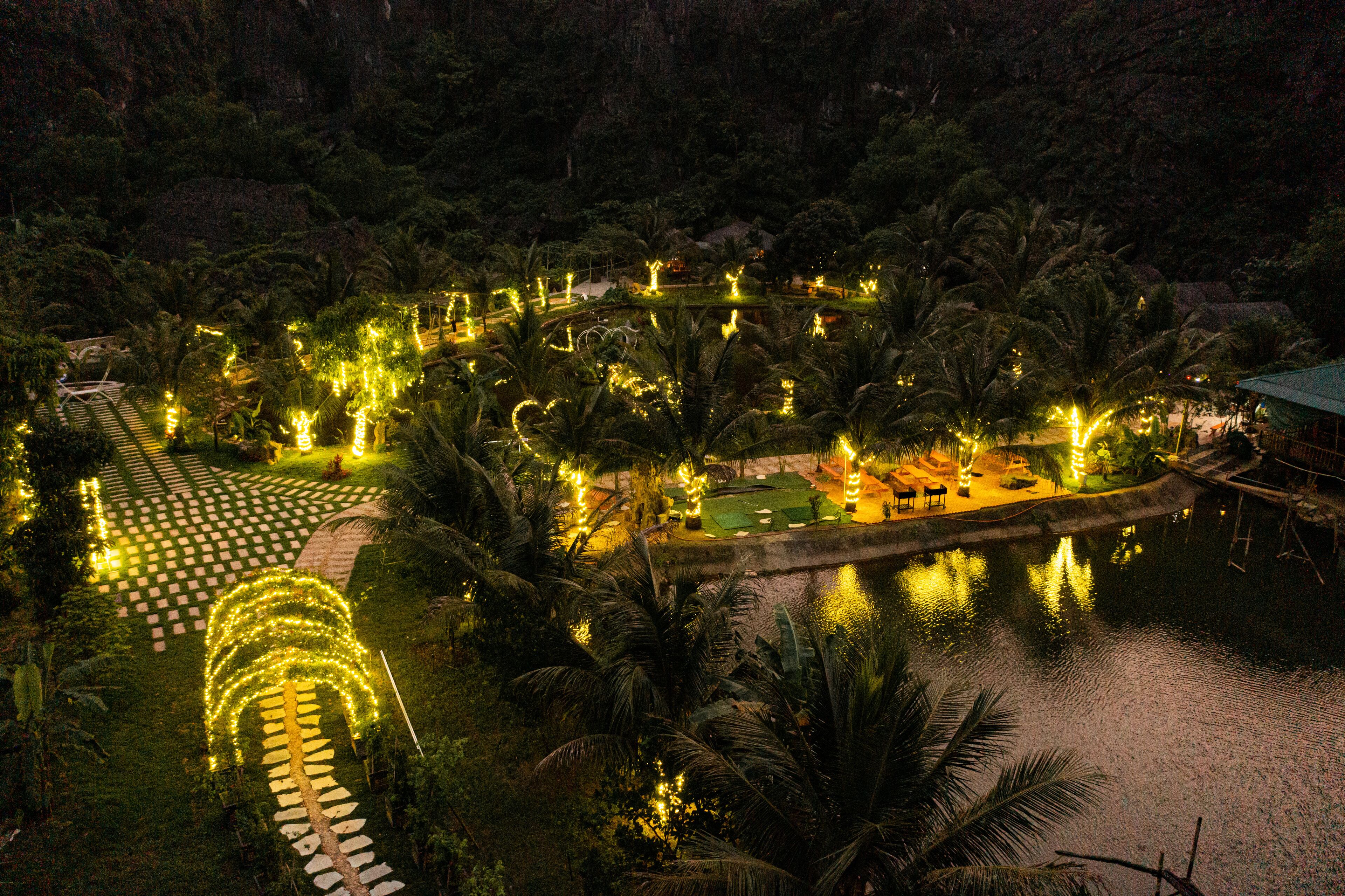 A resort with a water body, pathways, and illuminated trees.