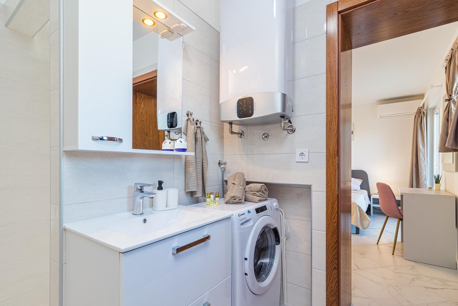 A modern bathroom with a built-in washing machine, a sink, and a mirror.
