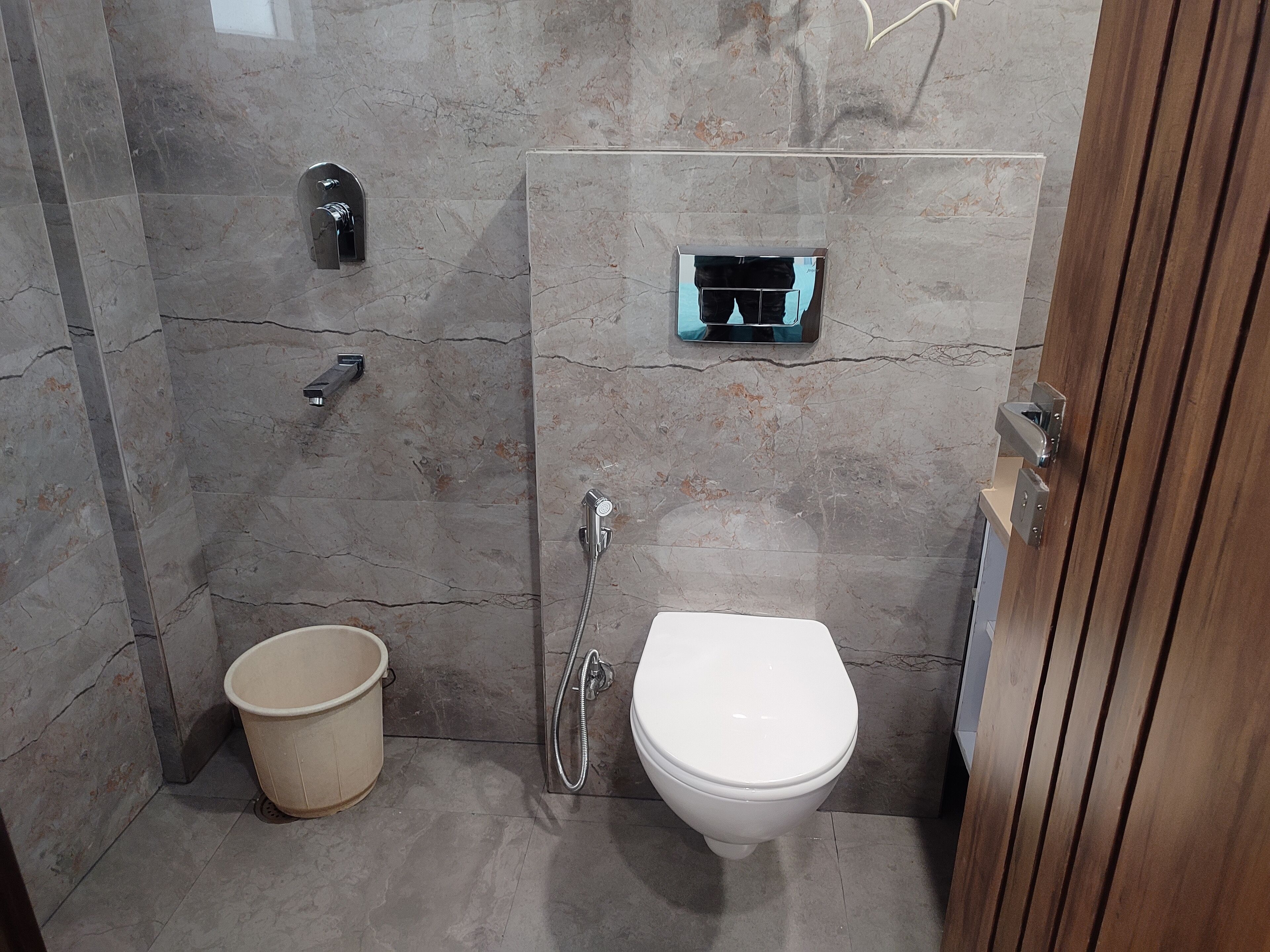 Une salle de bain moderne équipée d’une douche, de toilettes et d’un petit seau.