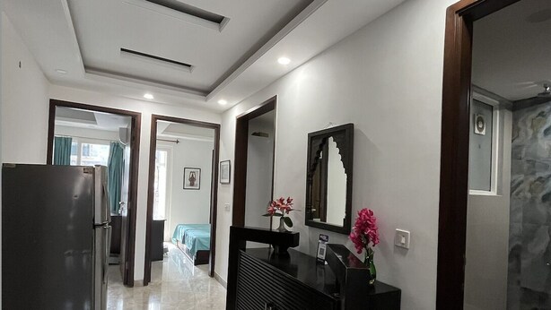A modern kitchen with a refrigerator, a dark wooden cabinet, and a marble floor. - Fully Furnished Room in Hauz Khas (New Delhi)