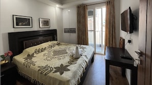A bedroom with a bed, a desk, a television, and a ceiling fan. - Fully Furnished Room in Hauz Khas (New Delhi)