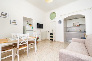 A modern living room with a dining area, a kitchen, and a TV mounted on the wall. - Rosa House – Private Terrace with Spectacular Views in the Heart of Positano (Positano)