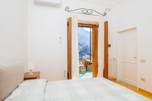 Une chambre à coucher avec un lit, une table de chevet, une fenêtre avec des rideaux et une vue sur une montagne.