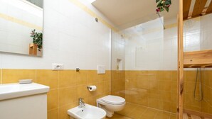 Een badkamer met toilet, bidet, wastafel en douche.