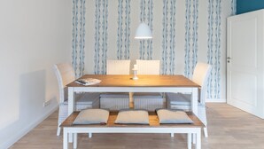 A dining area with a wooden table, white chairs, and a bench with cushions.