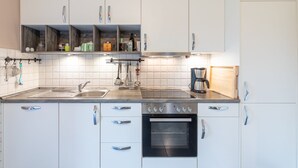A modern kitchen with white cabinets, a stainless steel sink, a coffee maker, and an oven.
