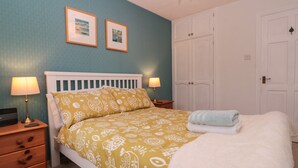 Une chambre à coucher comprenant un lit, deux tables de chevet, une armoire et deux tableaux encadrés accrochés au mur.