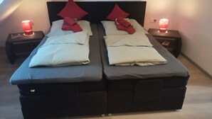 Ein Doppelbett mit schwarzem Kopfteil, zwei Nachttische mit roten Lampen und ein kleiner Nachttisch mit einer roten Kerze.