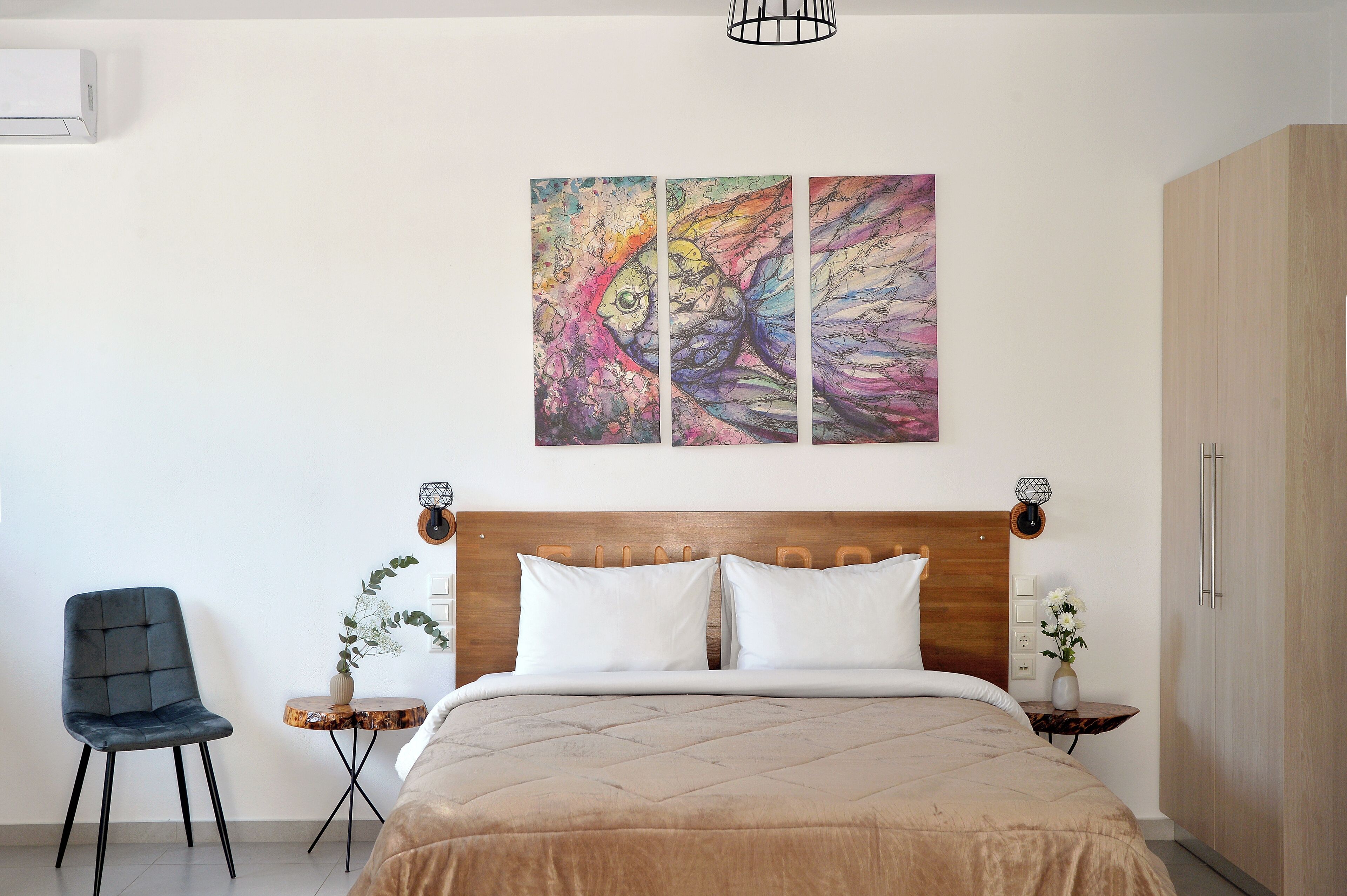 A bedroom with a bed, a chair, a small table, and a wall-mounted air conditioner.